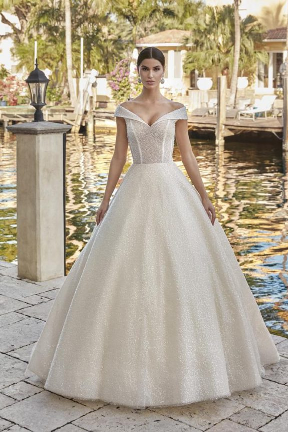 Model in a shimmering off-the-shoulder ballgown on a sunlit stone terrace