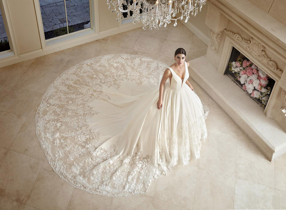 Bride in an ivory ballgown with a lace-edged train in a chandelier-lit salon